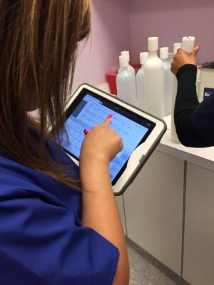 Dental assistant checking supply inventory on tablet